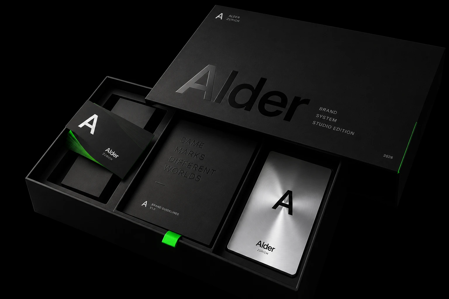 Alder's black presentation box, its lid lettered Brand System, Studio Edition, open on a stack of black cards with green edges, the brand guidelines and a brushed-metal card.