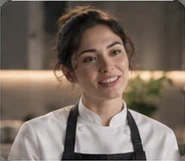 The cook in the white jacket, smiling, close up.